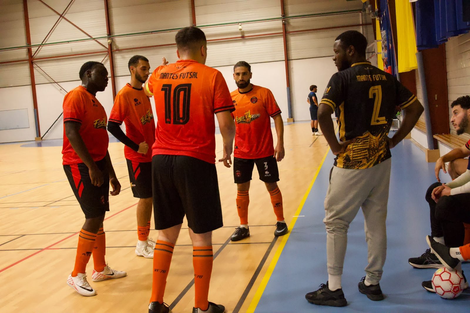 Joueurs de Mantes Futsal en maillots orange et noir Atls autour de leur coach